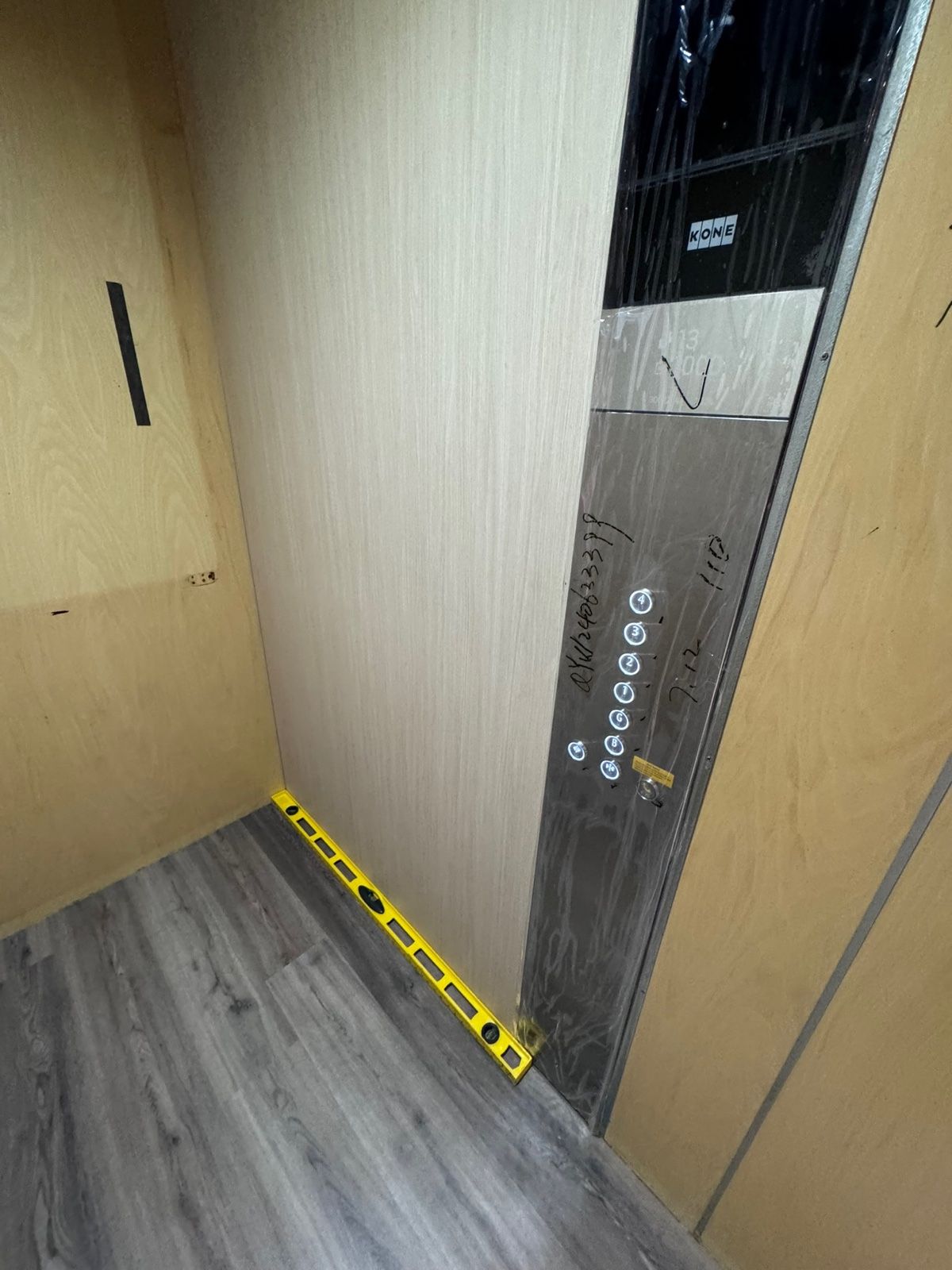 Installation in progress: Lift car, raw plywood to light woodgrain
