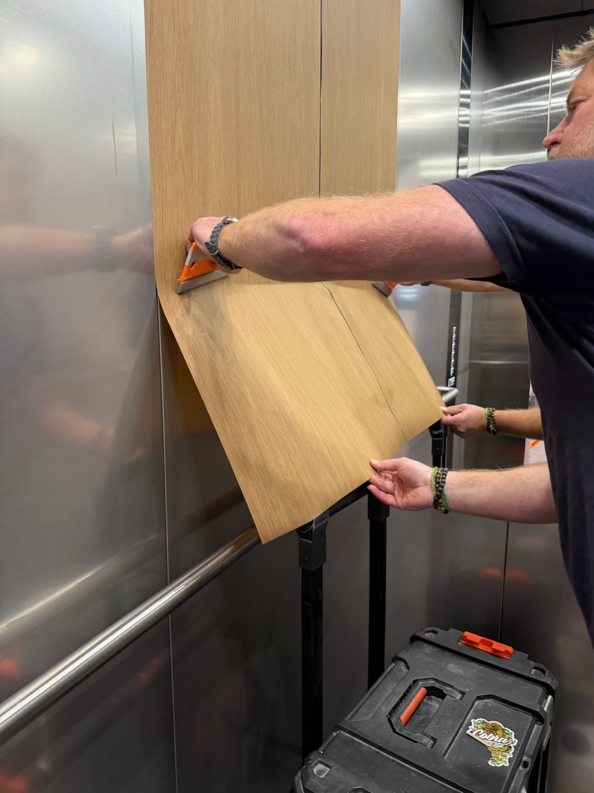 Installation in progress: Lift car, stainless to light woodgrain